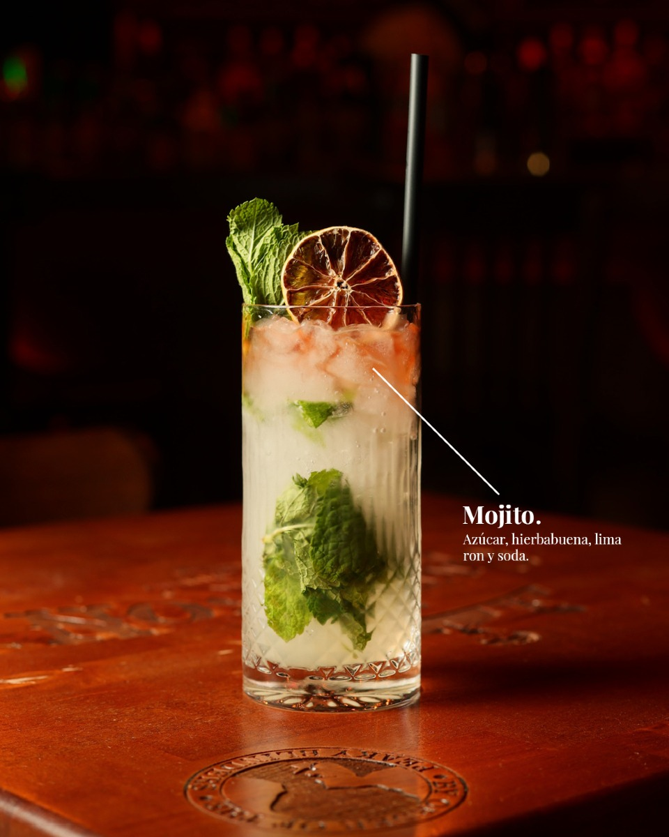 Mojito con menta, lima y rodaja de cítrico deshidratado sobre la barra grabada del local